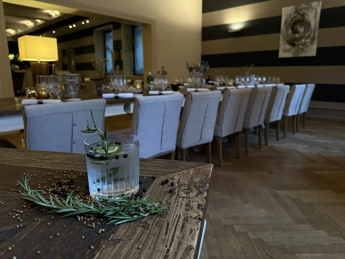Gin Tonic mit Rosmarin vor einer gedeckten Tafel